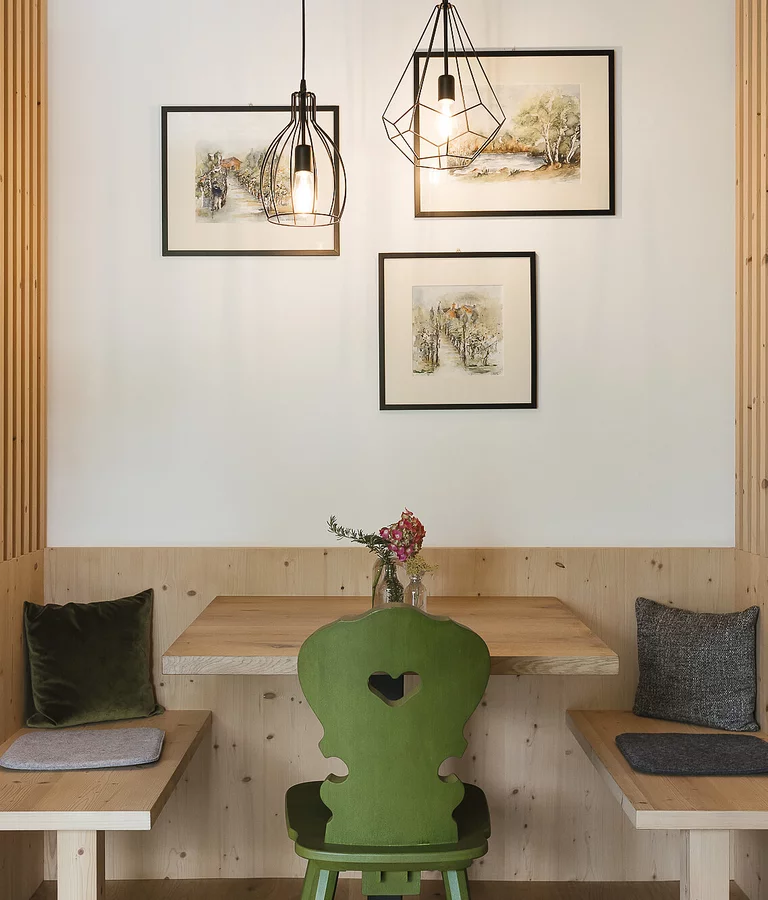Hotel Südtirol Urlaub am Bauernhof Sitzecke in Holz und grünem Stuhl.