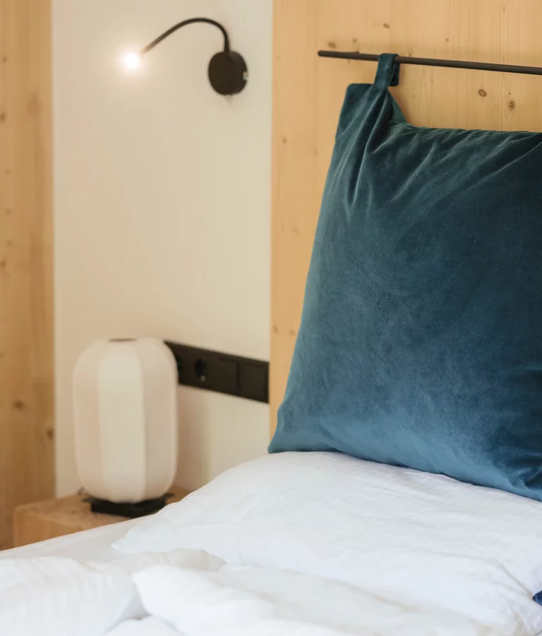 Hotel Südtirol Detail Bett mit blauen Kissen. Ferienwohnung.