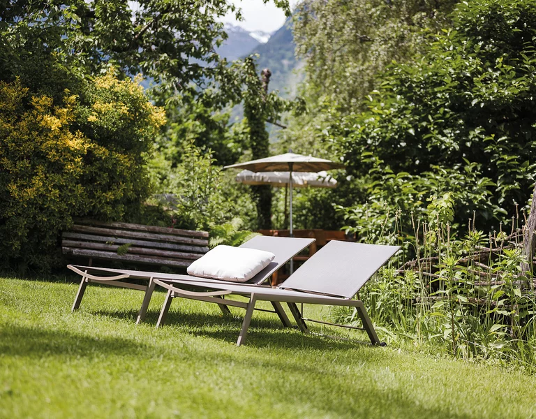 Zwei Gartenliegen im grünen wilden Garten